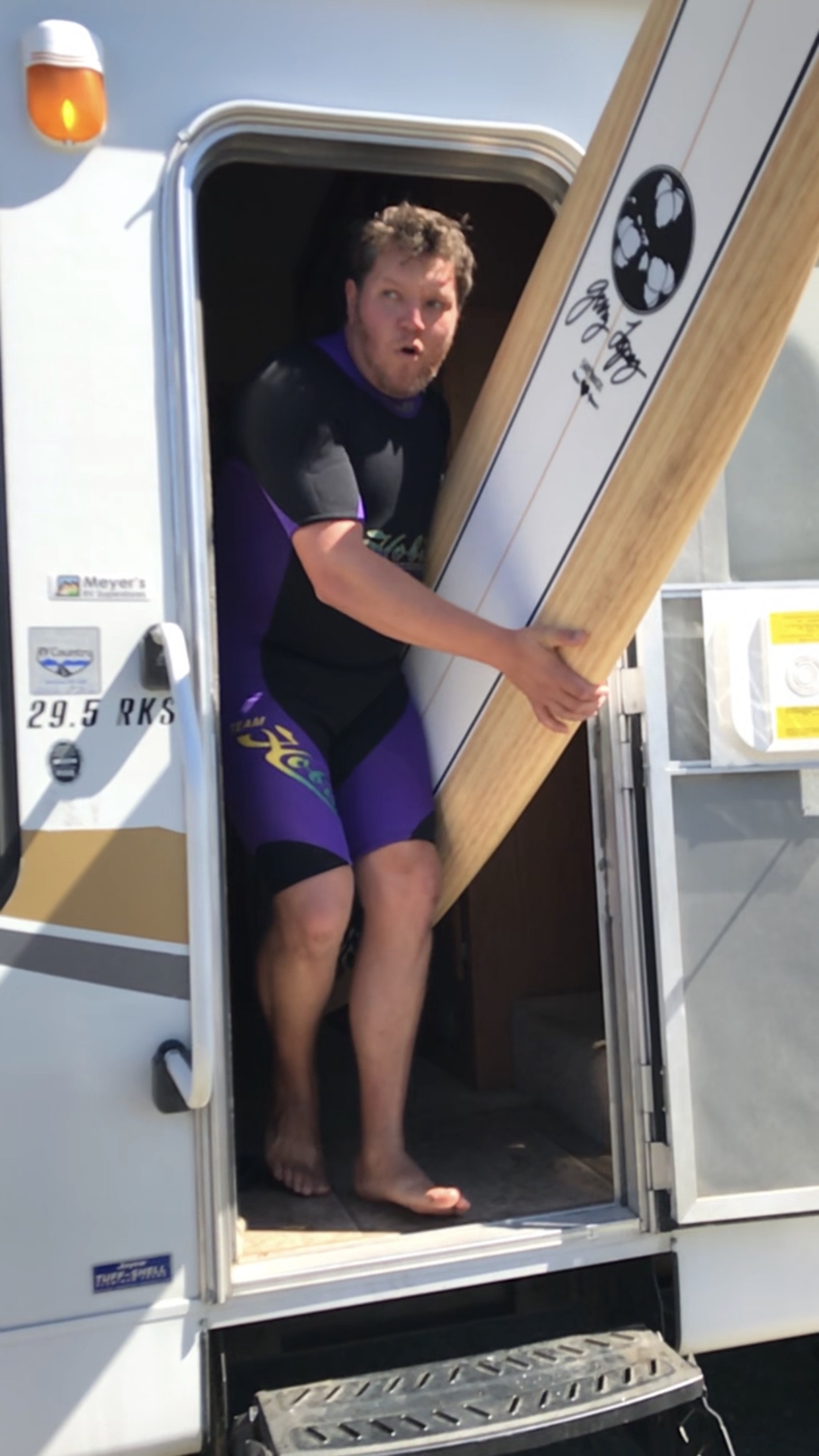 Matthew carrying an oversized wooden paddle out of a camper